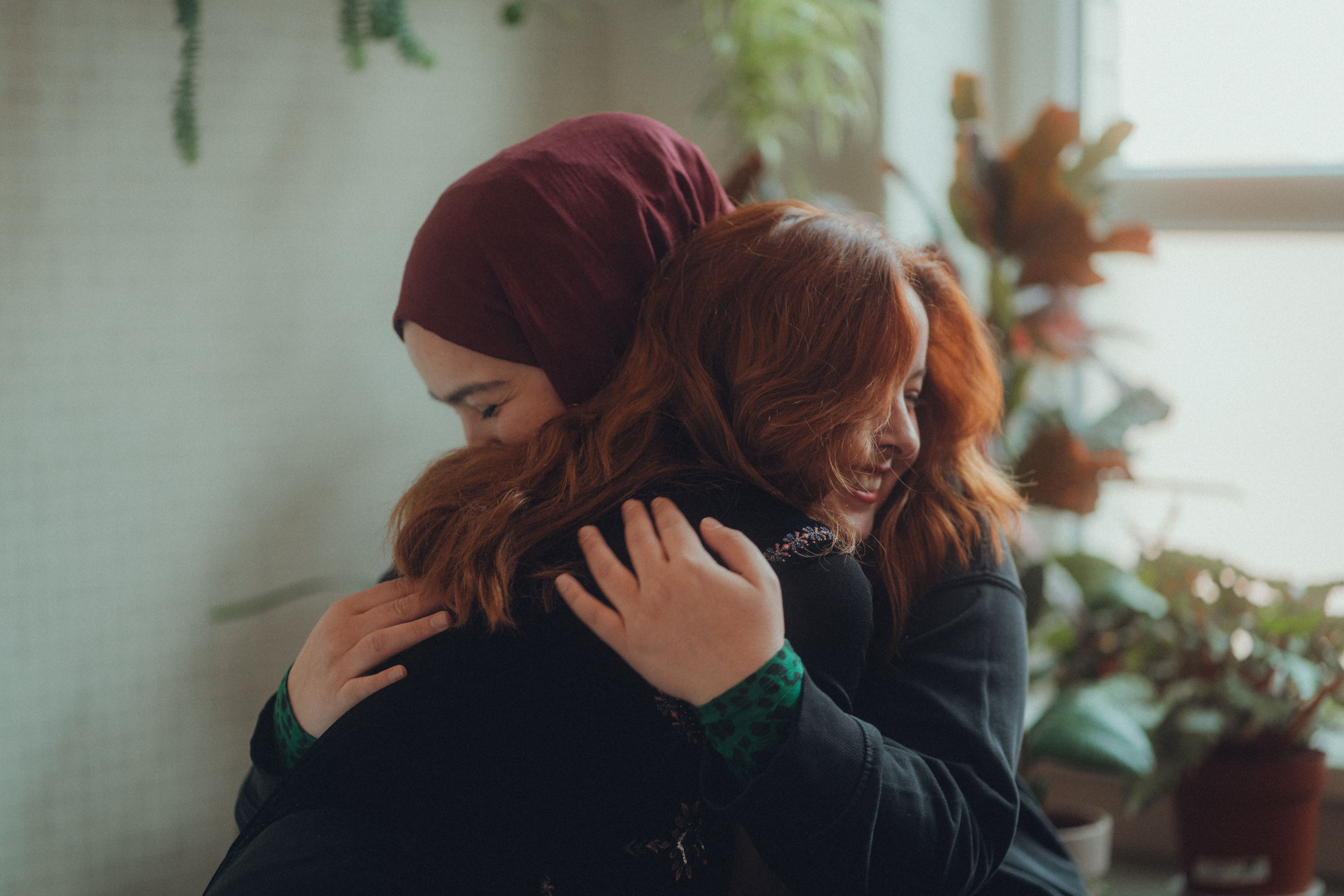 Two women embracing warmly indoors, representing affection and meaningful connection