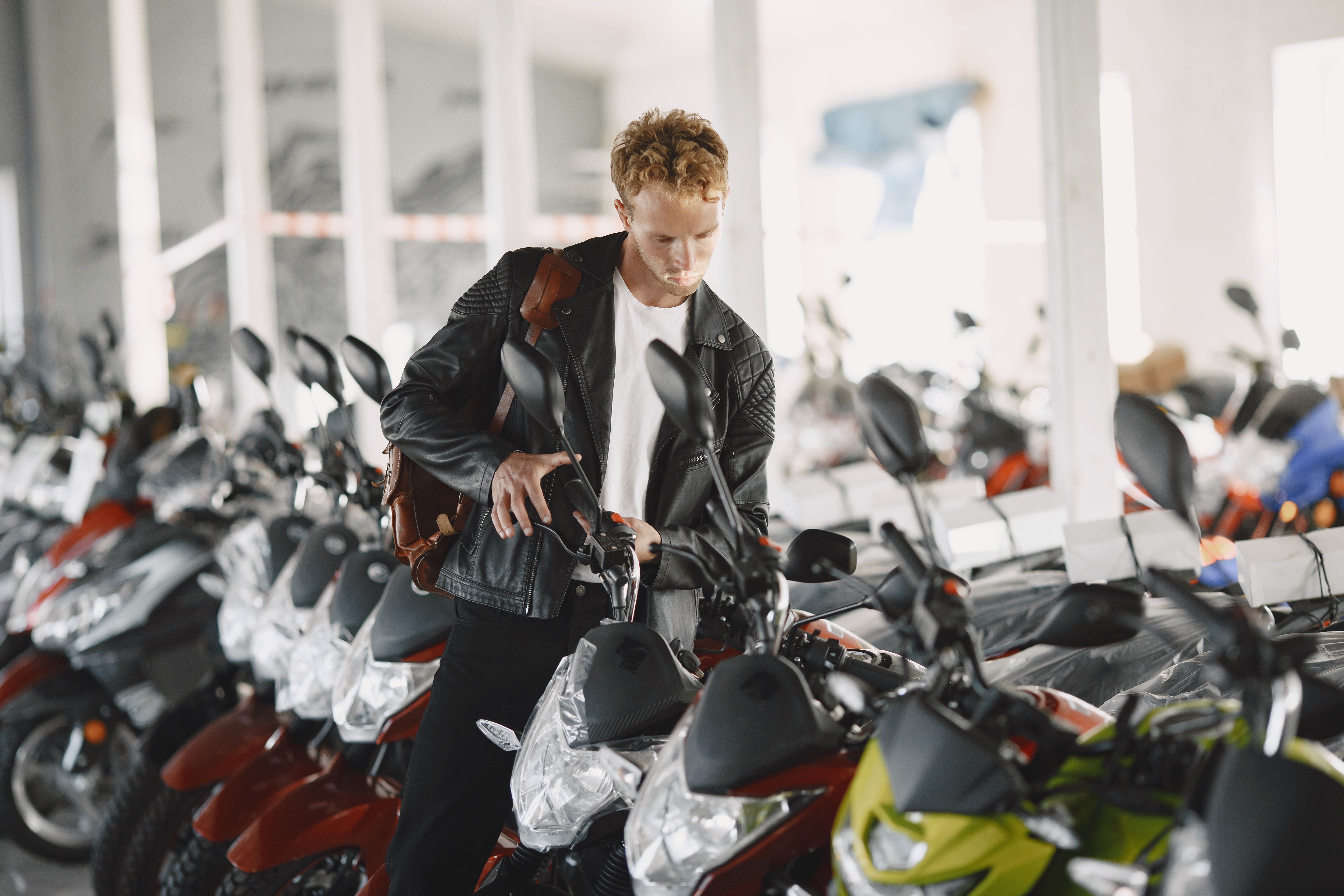 Young man inspecting a row of motorcycles at a motor dealership showroom