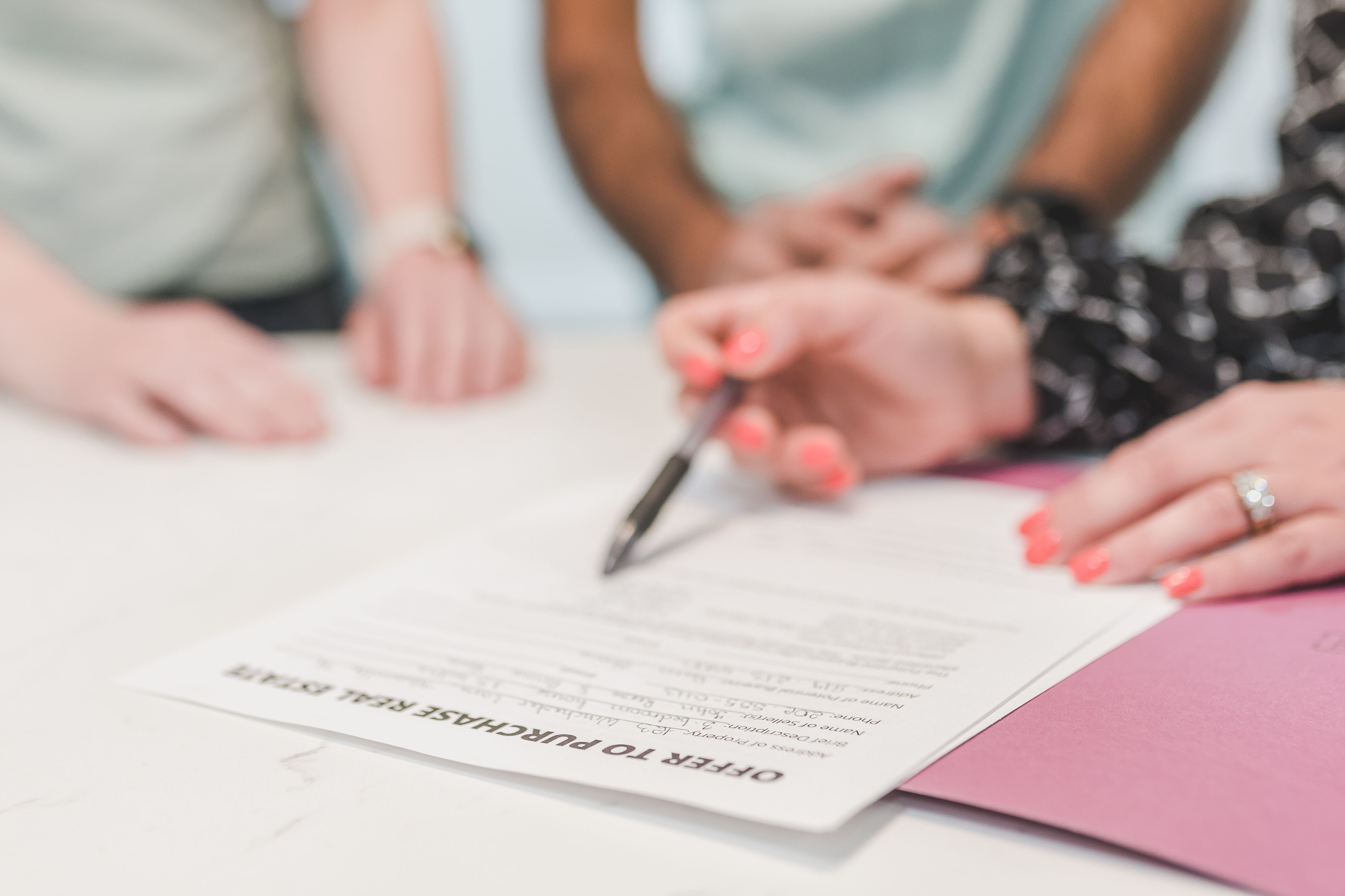 Close-up of people reviewing and signing a purchase offer document