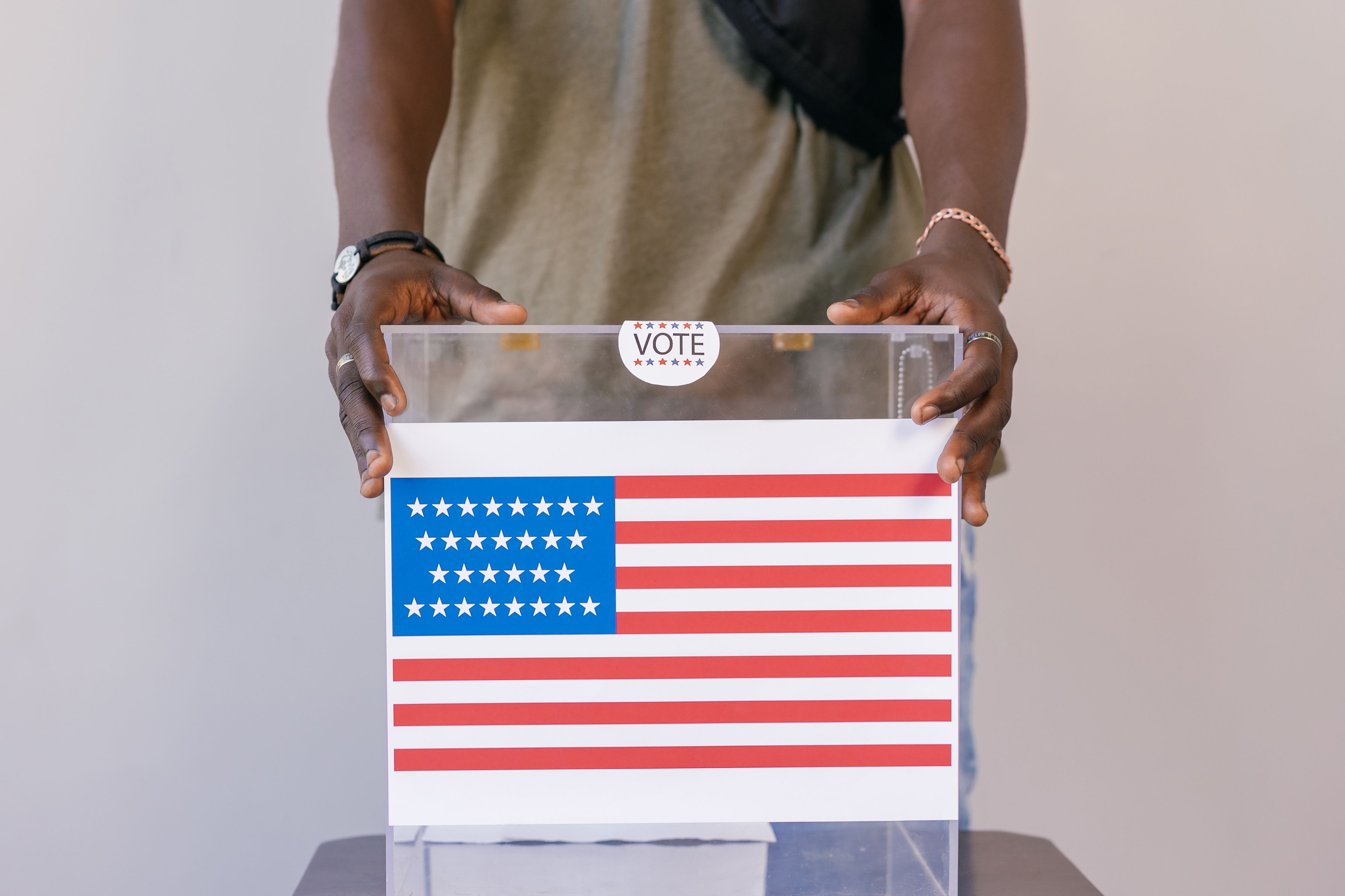 Close-up of a person placing a vote in a transparent ballot box