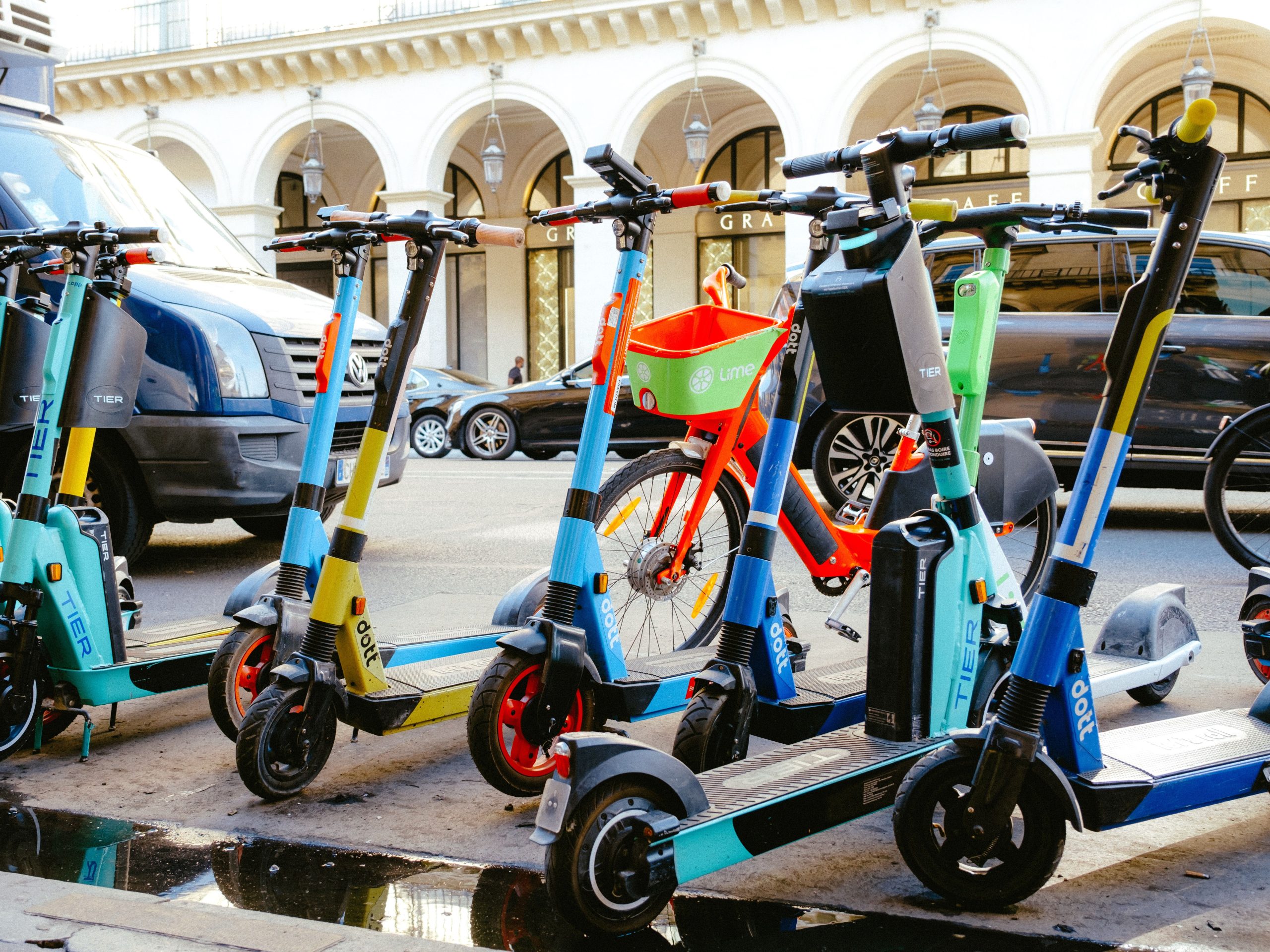 A vibrant collection of electric scooters and bicycles parked on a bustling city street